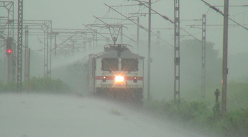 In  heavy rains, GZB WAP-7# 30223 enters Kelve Road  with 12926 Amritsar/Kalka Bandra Terminus Paschim E